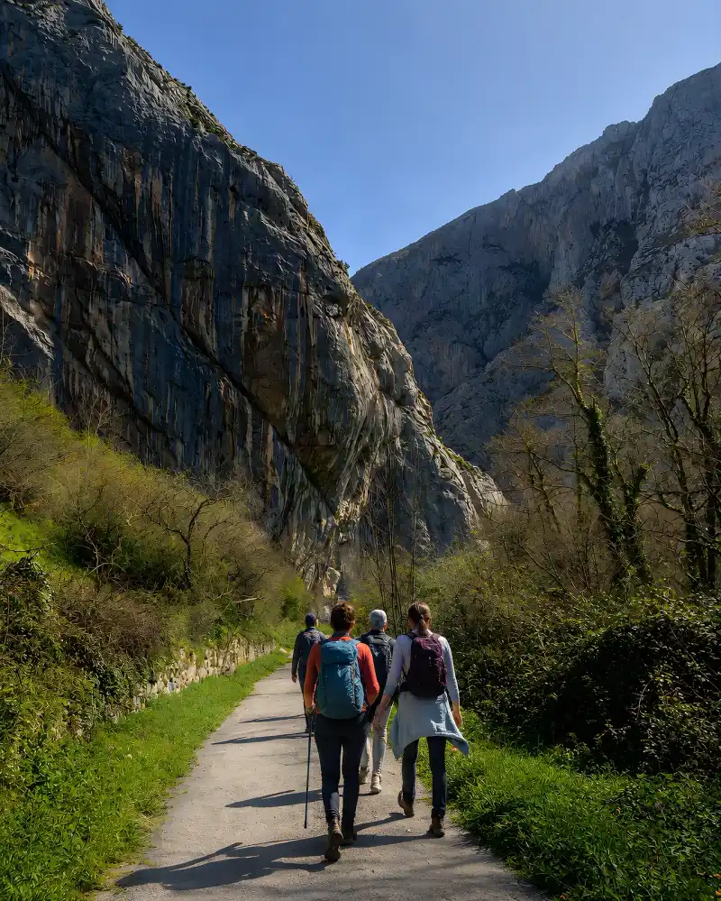 Senderistas caminando por la senda bajo las paredes calizas del desfiladero